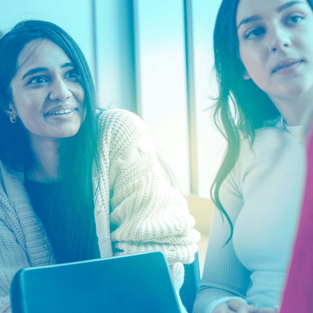 Two female students talking to a third person out of shot, blue tint over the image.